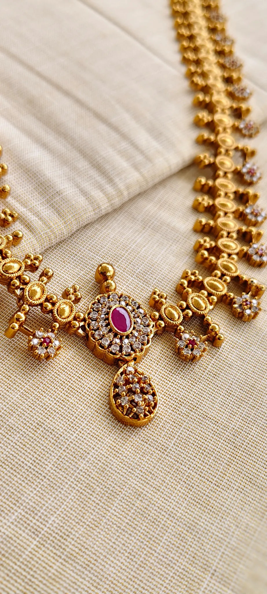 Gold necklace with gemstones on a beige fabric background