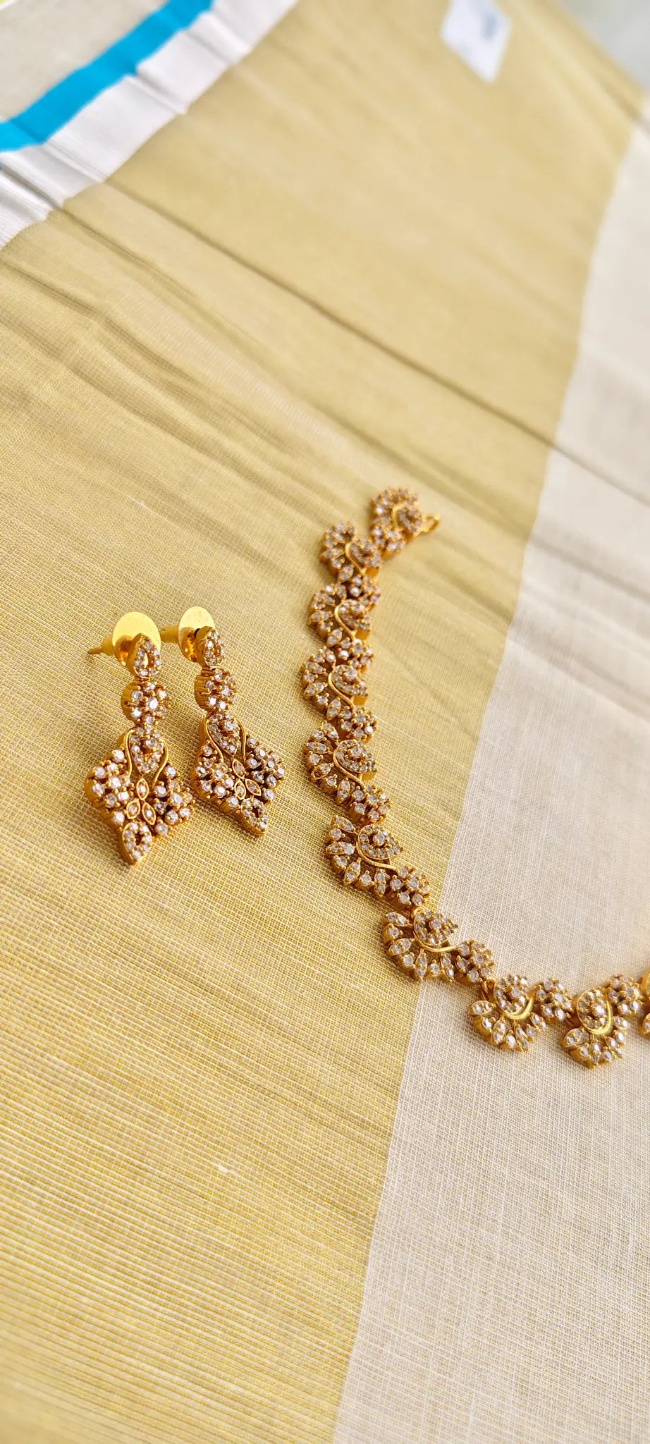 Gold necklace and earrings on a beige fabric background