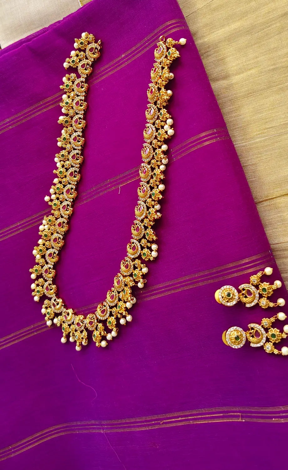 Gold necklace with floral designs on a purple fabric background