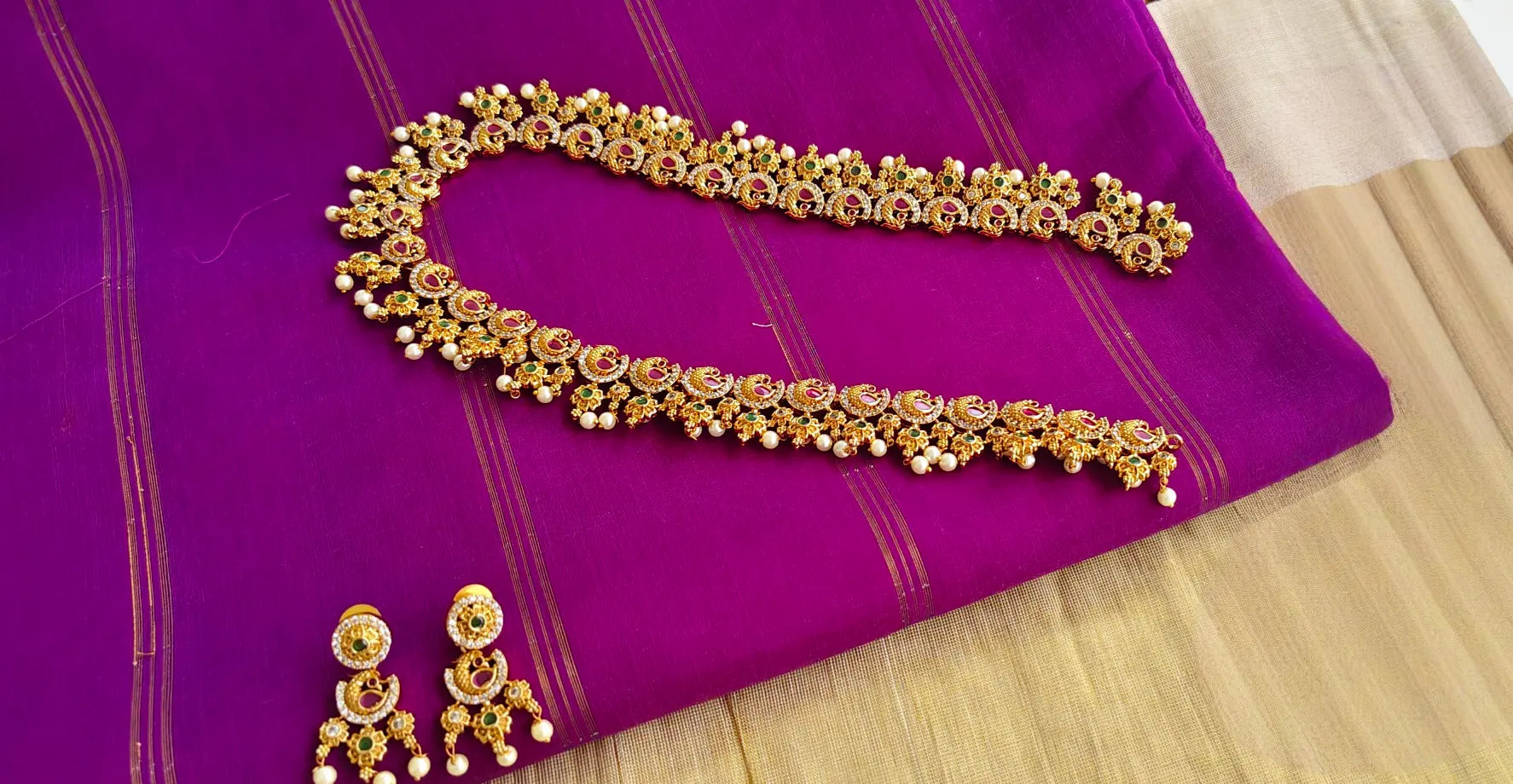 Gold necklace and earrings on a purple fabric background