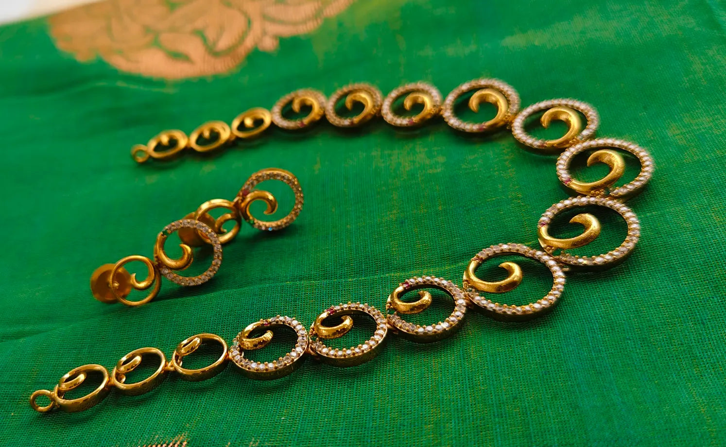 Gold bracelet on a green fabric background
