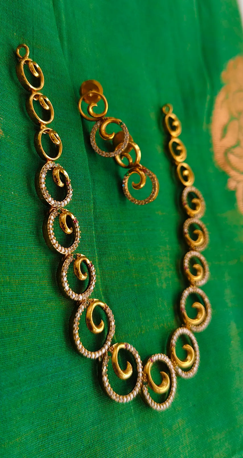 Gold necklace and earrings on a green fabric background