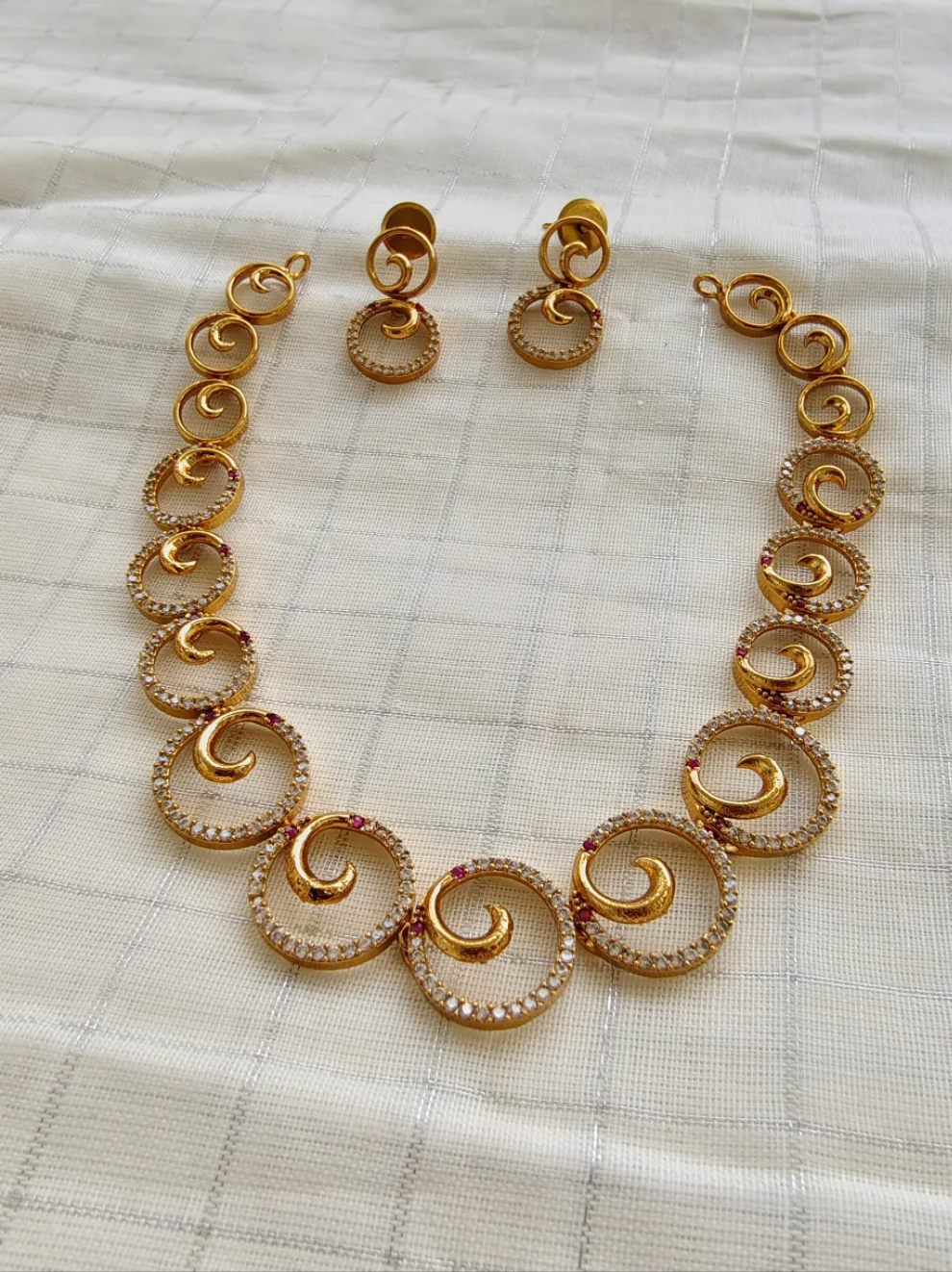 Gold necklace and earrings on a textured white surface