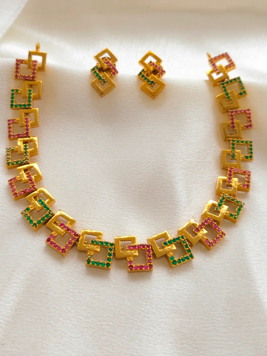Gold necklace and earrings with colorful gemstones on a white background