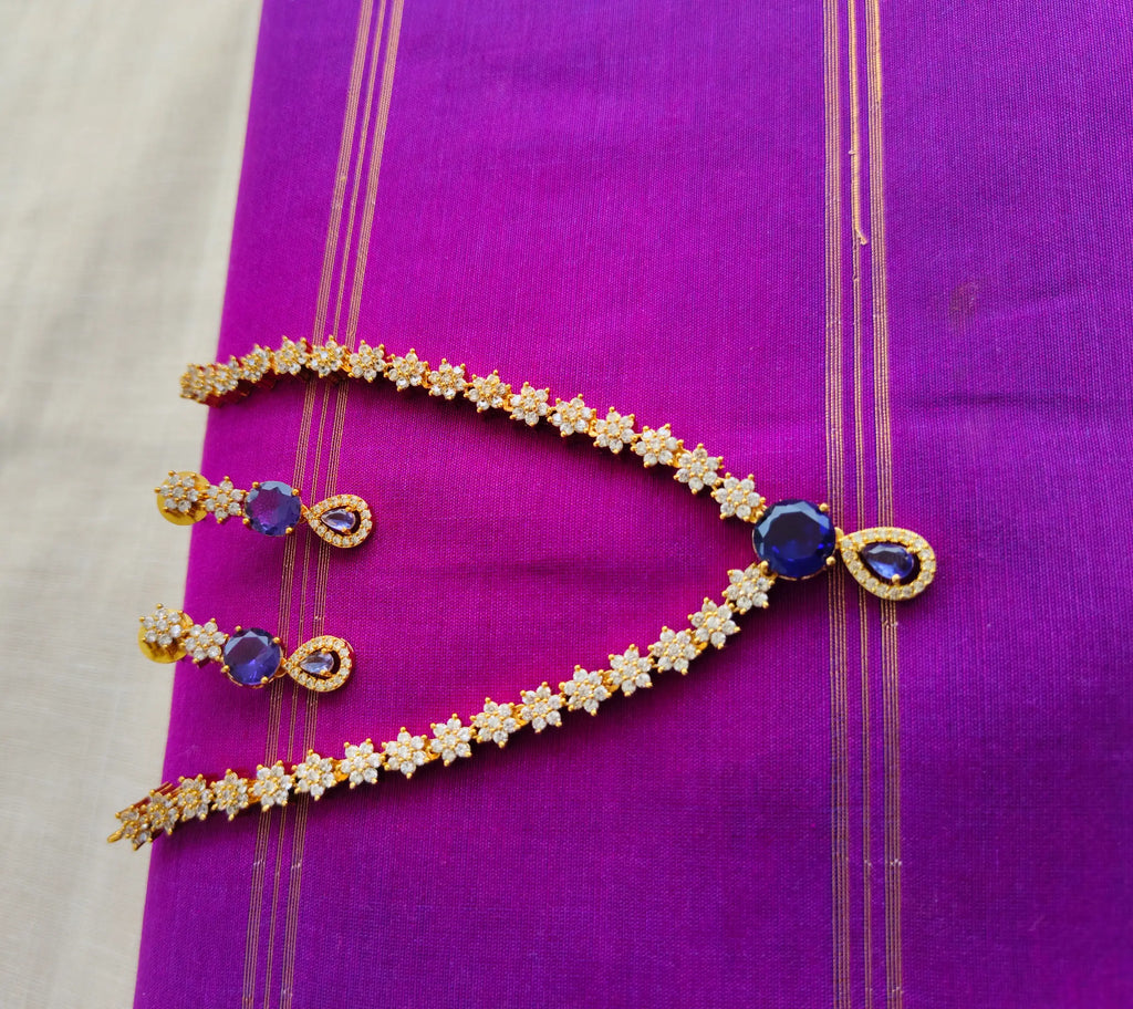 Gold necklace with blue stones on a purple fabric background