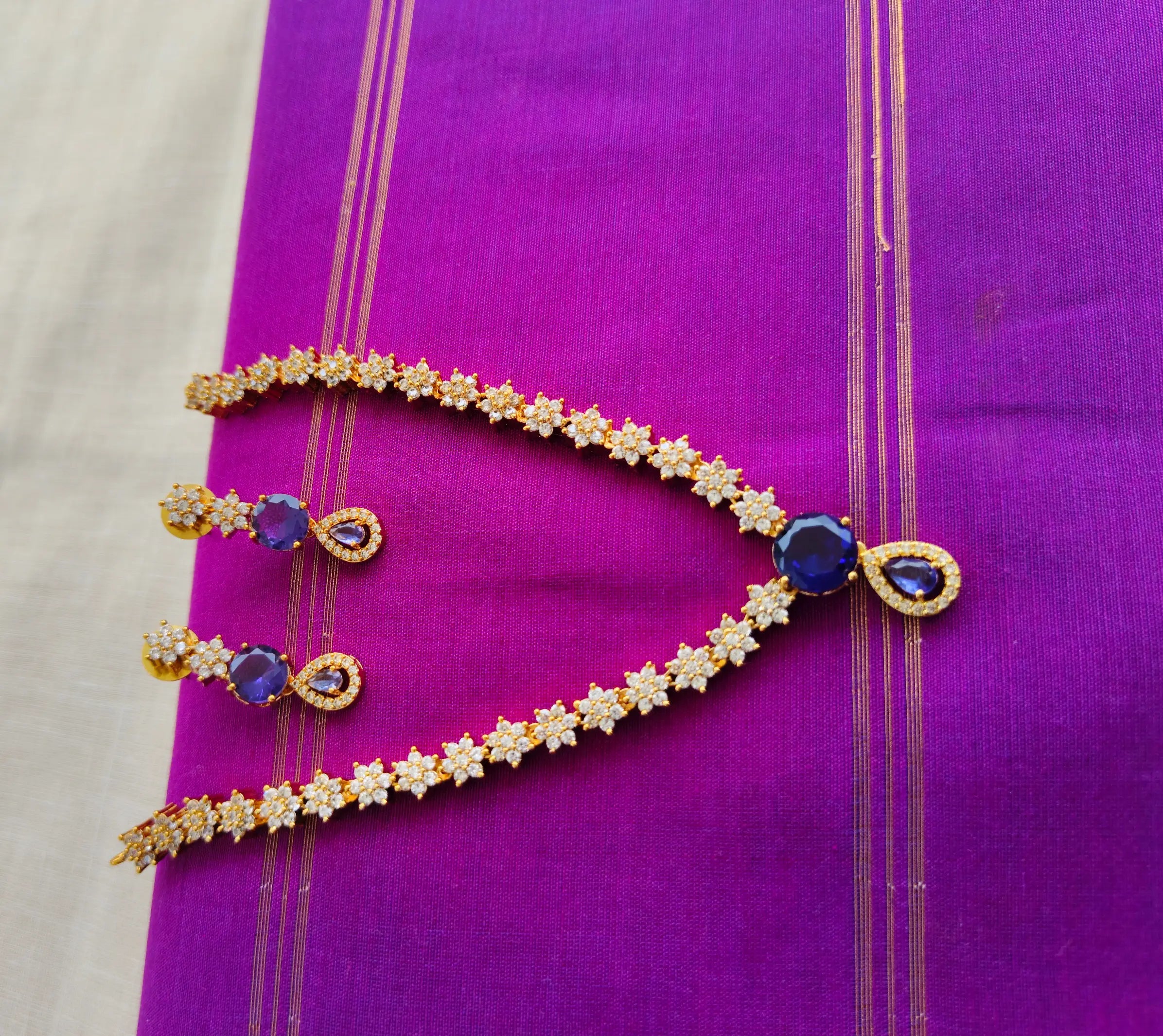 Gold necklace with blue stones on a purple fabric background