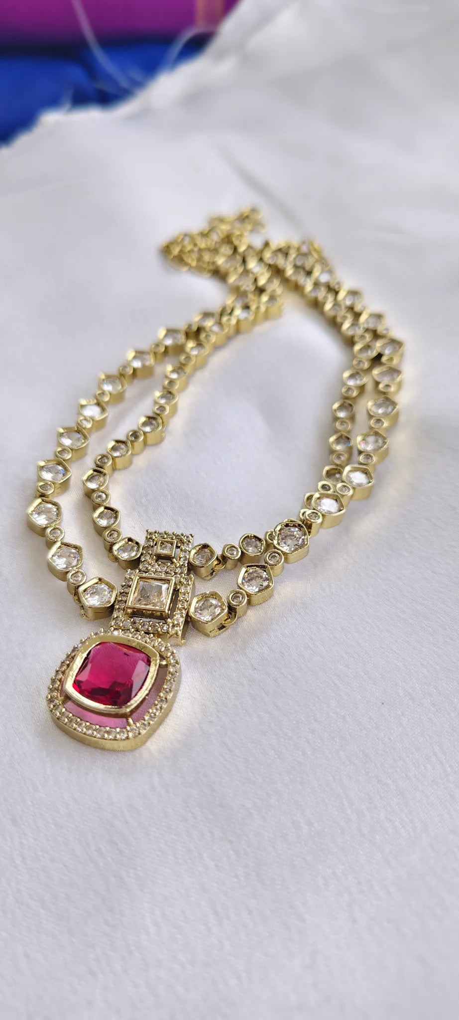 Gold necklace with a pink stone pendant on a white background